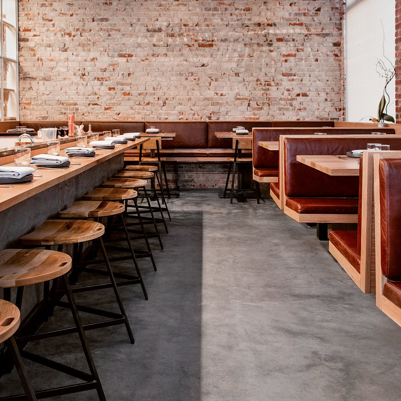 The Wolf’s Tailor in Denver, CO showcases Denver Modern’s contract-grade bar stools with wood seats and steel bases, paired with leather booths and exposed brick walls.