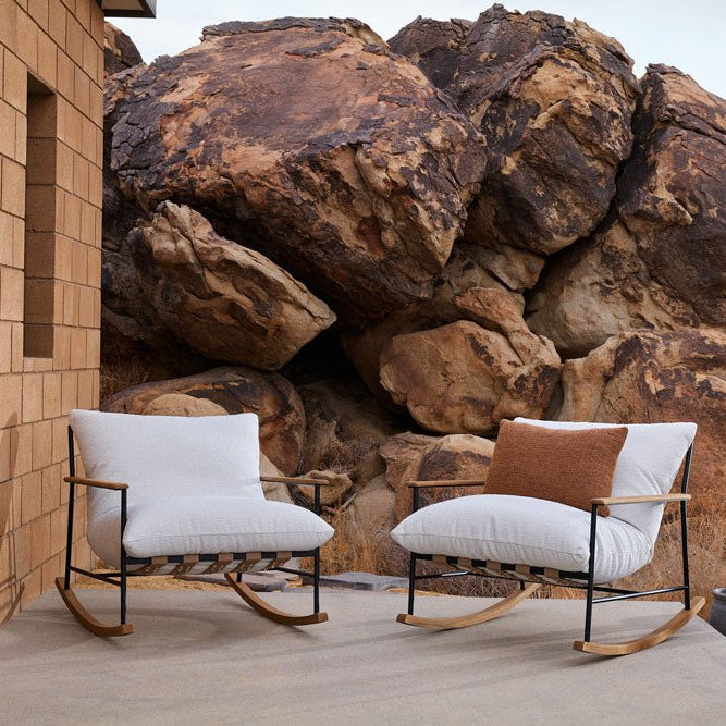 Modern Outdoor Vail Rocking Chairs with white cushions and wood-accented frames, set against large desert boulders with potted cacti.