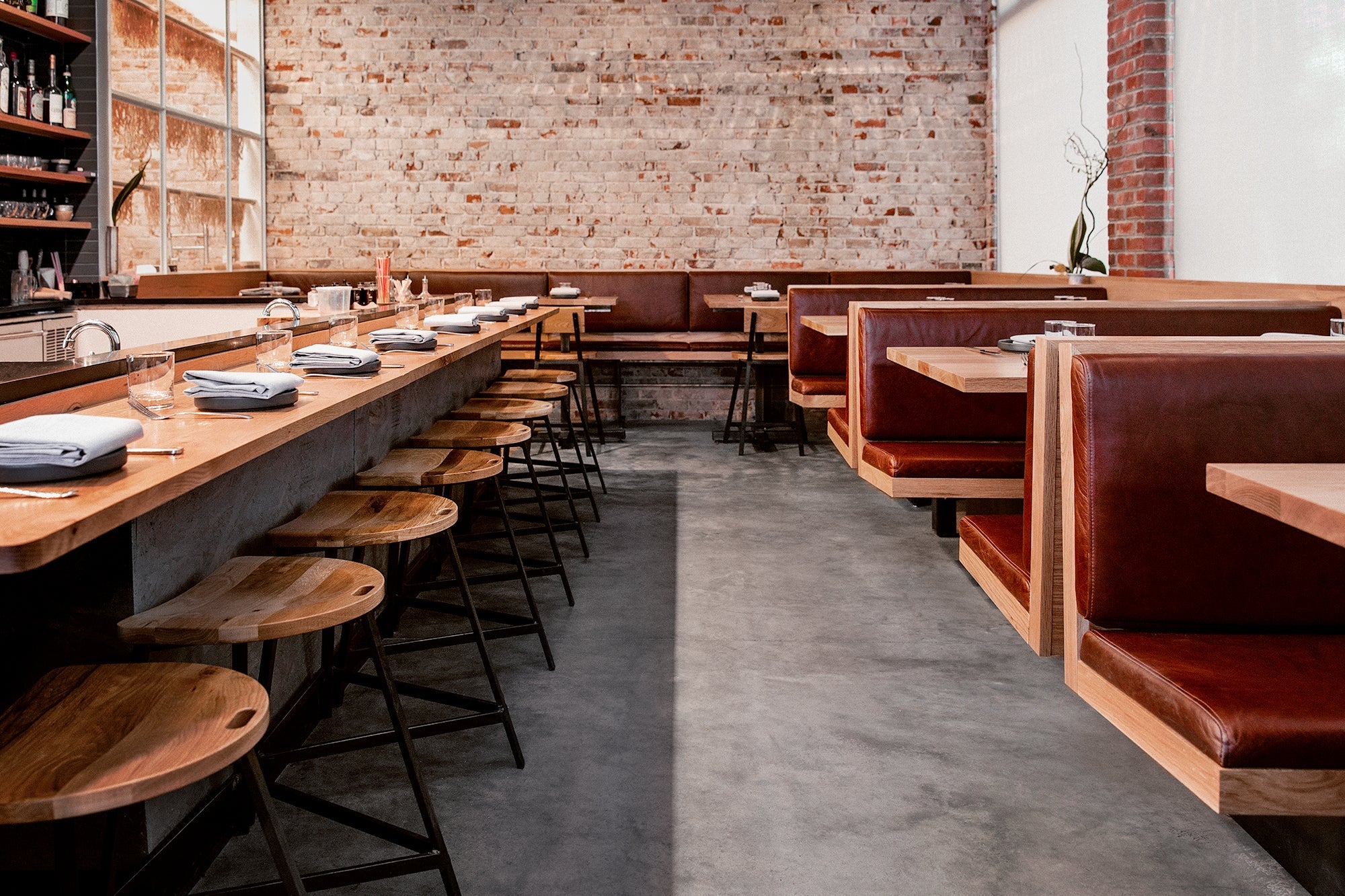 The Wolf’s Tailor in Denver, CO showcases Denver Modern’s contract-grade bar stools with wood seats and steel bases, paired with leather booths and exposed brick walls.