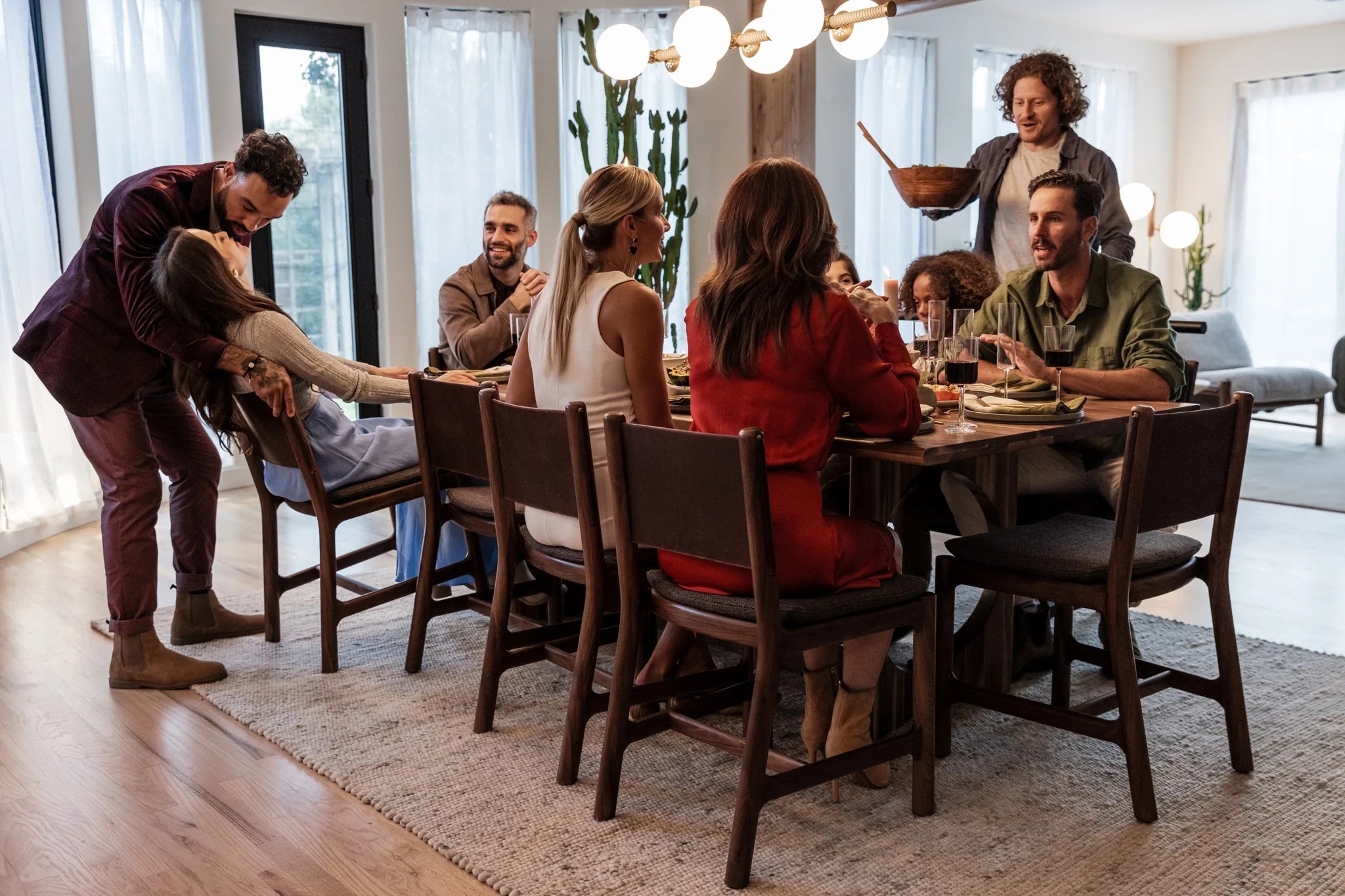 Modern dining room with wood dining table and chairs, featuring a group enjoying a shared meal in a warm, contemporary setting.