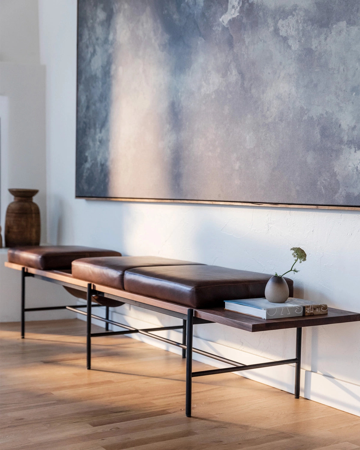 Modern interior with a leather Aspen Bench and abstract painting on the wall.