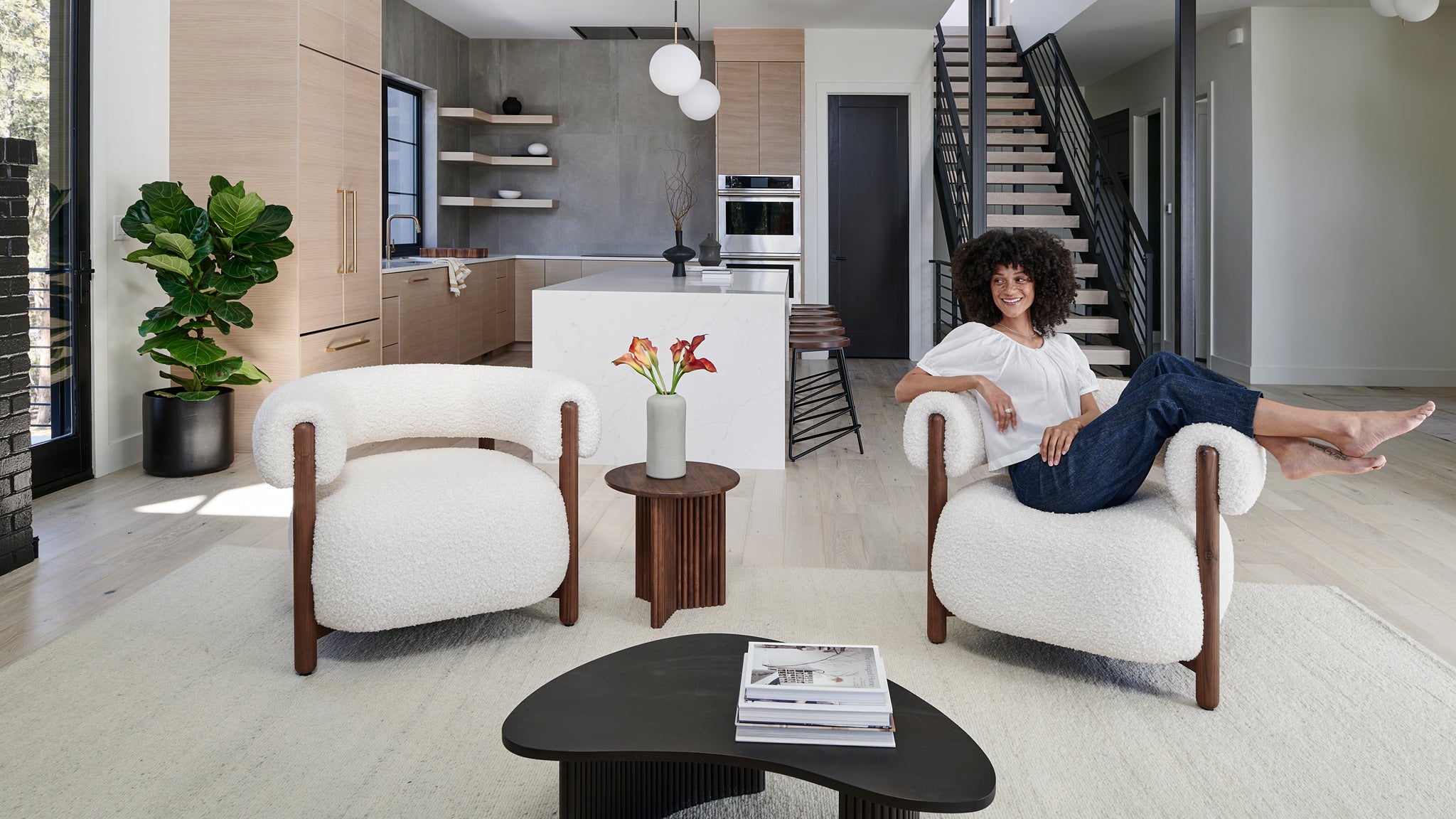 A joyful woman lounges in a chic, modern living room with stylish furniture and bright decor.