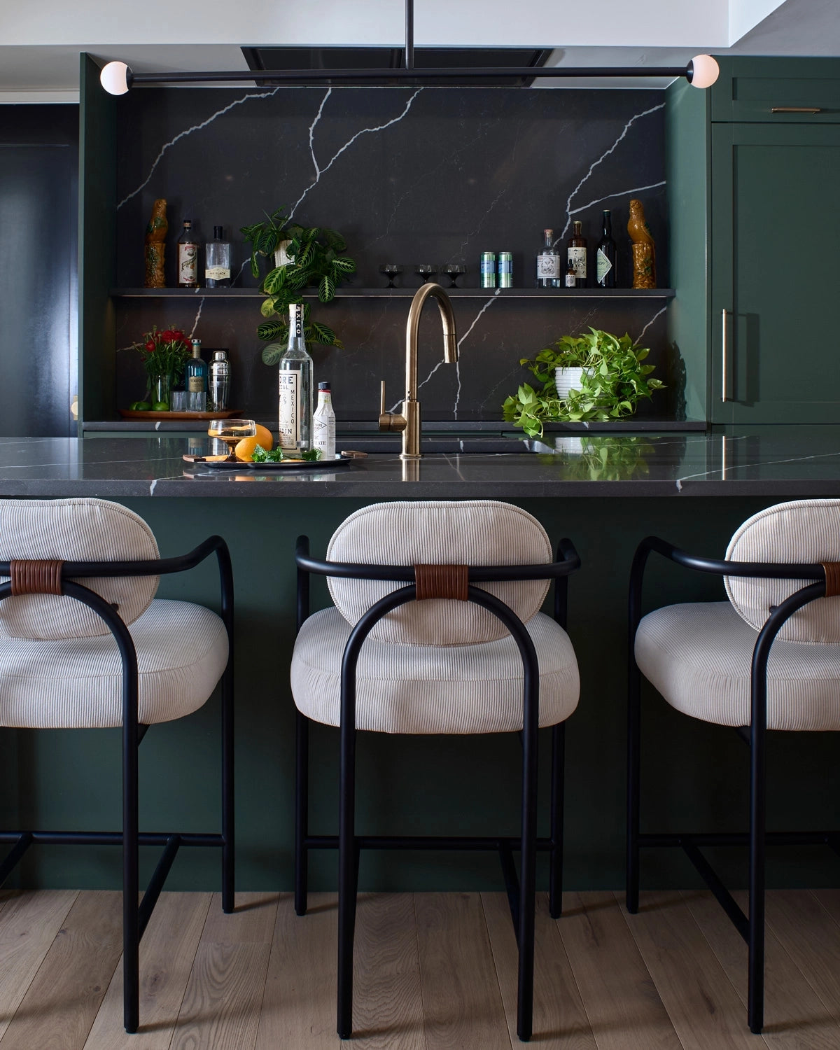 Modern kitchen with dark green cabinets, marble countertop, and the Arches Counter Stools in Cream Corduroy.