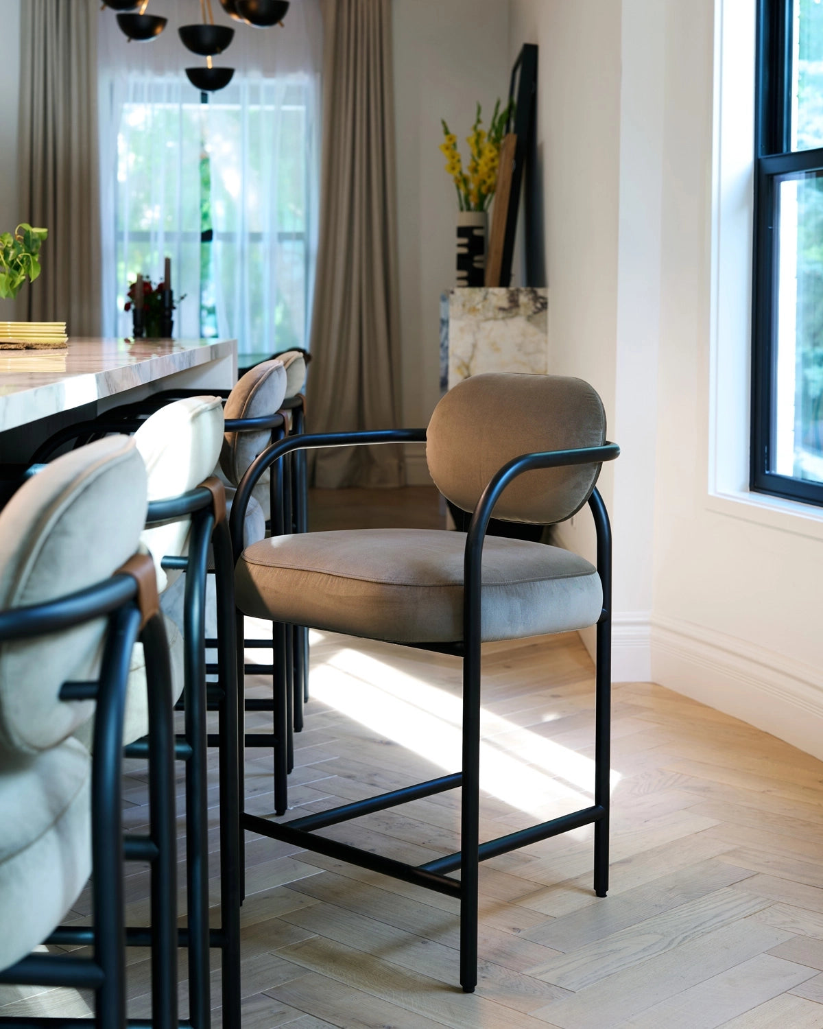 Dining area with Arches Counter Stools in Mushroom Velvet and black metal legs in a well-lit room.