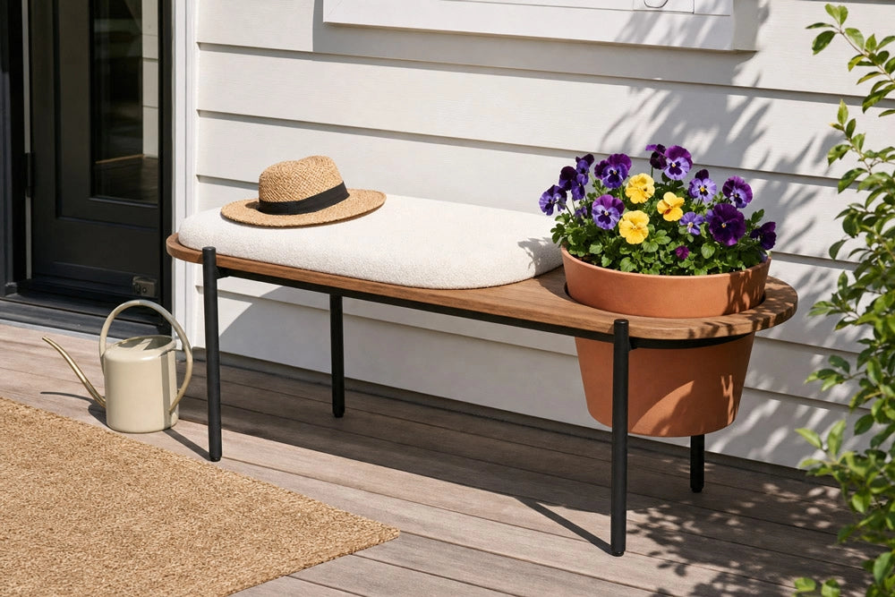 Wooden bench with a straw hat, white cushion, and potted flowers on a wooden deck.
