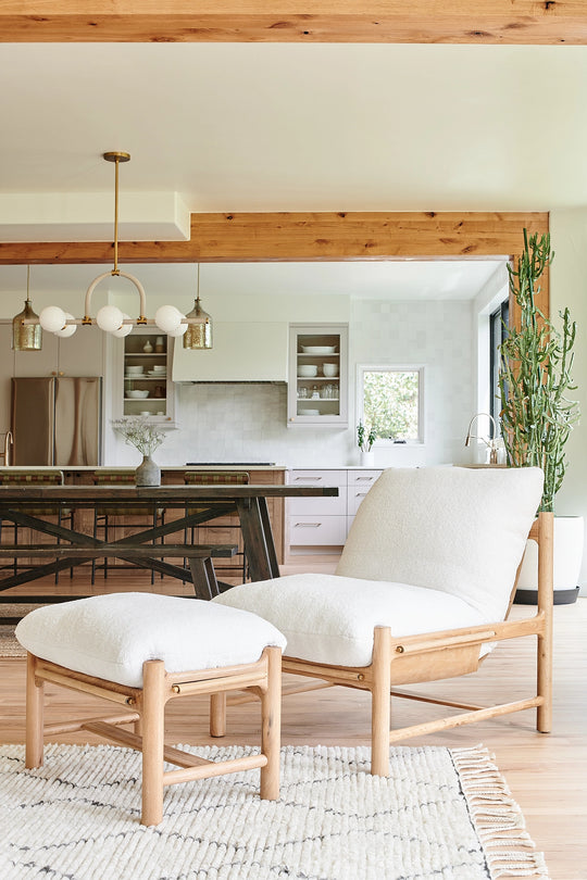 a white chair and stool in a room with a kitchen