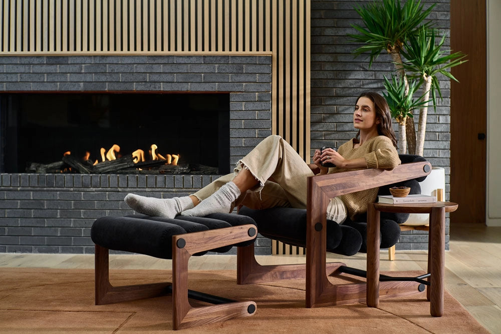Woman sitting in a modern living room with a fireplace and the Durango Lounge with the matching Durango Ottoman.