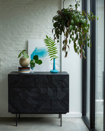 a black dresser with a blue vase and a plant from it