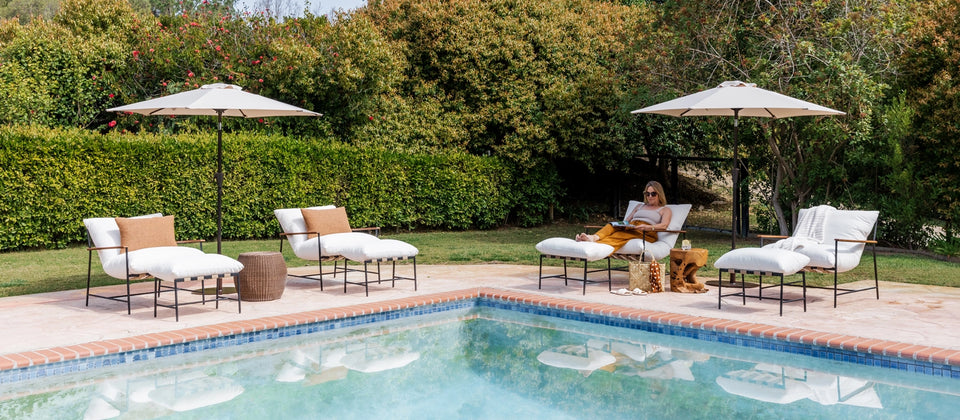 a woman sitting in a chair by a pool