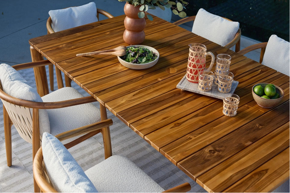 Outdoor Dillon Dining Table with chairs, glasses, and a bowl of fruit on a patio.