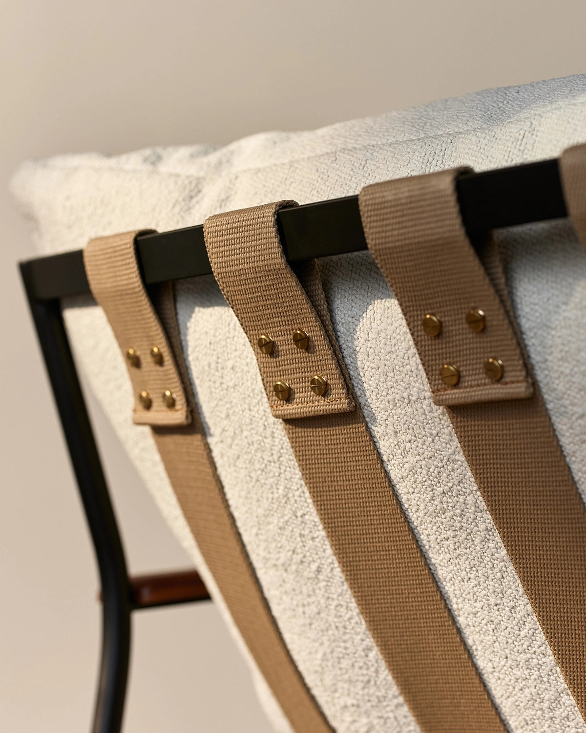 Close-up of Outdoor Vail Lounge backrest showing woven upholstery, tan webbing straps, and powder-coated steel frame
