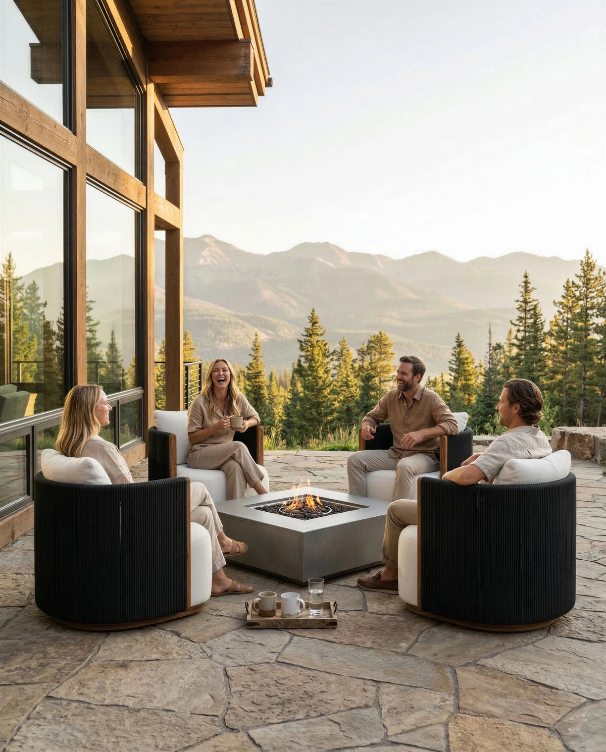 People sitting on the Outdoor Spruce Swivel Lounge around a fire pit on a patio with mountain views