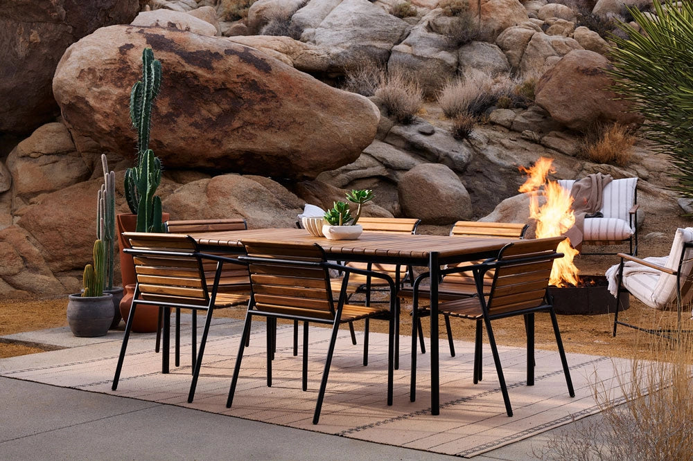 Outdoor patio set with the Strata Dining Table and Strata Dining Chairs, and fire pit against a rocky desert backdrop.