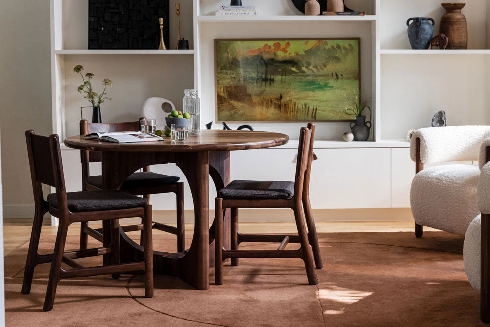 Dining area with a Summit Round Dining Table and Avon Dining Chairs in a room with a painting on the wall.