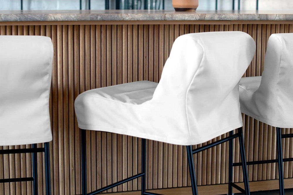 Vail Counter & Bar Stools with a removeable cover with black legs against a wooden panel wall.