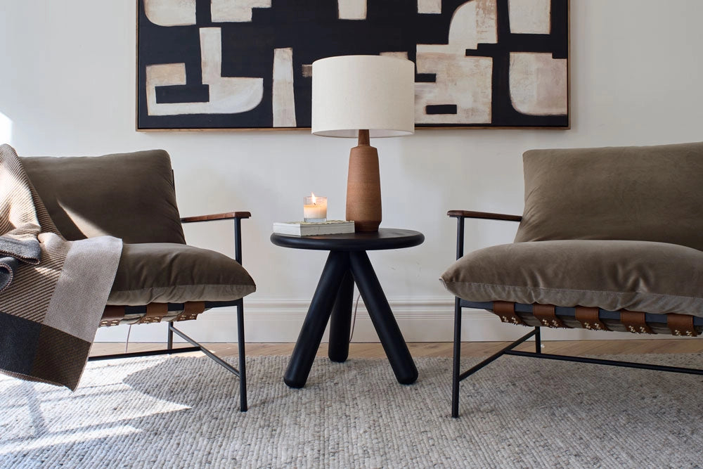 Modern living room with two brown chairs, a Willow Side Table, and abstract art on the wall.